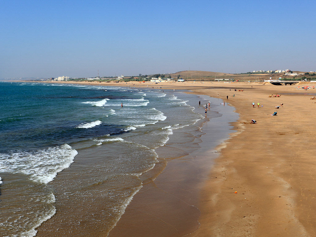 waves crash on the shore of the beach in Asilah, Morocco
