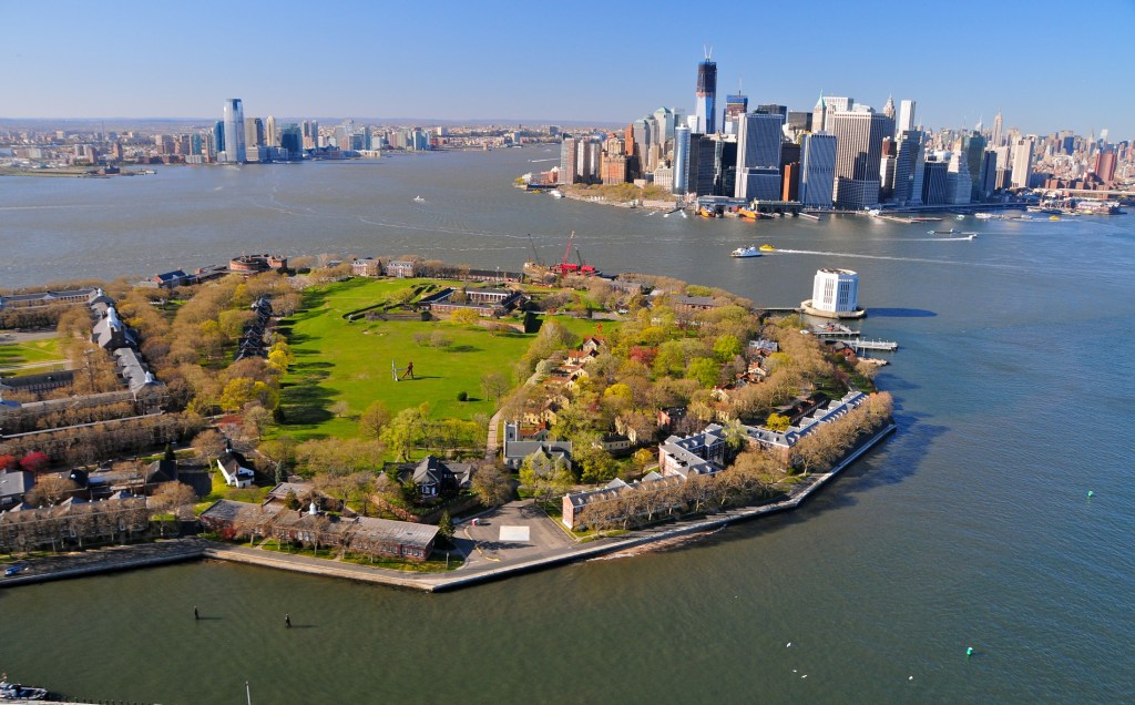 Aerial view of an island in a harbor, with green fields and buildings
